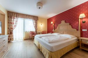 una camera con un grande letto e una parete rossa di Hotel Obereggen a Obereggen