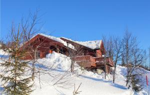 a log cabin on a snow covered hill with a tree at Cozy Home In Tuddal With Kitchen in Tuddal