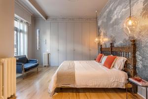 um quarto com uma cama grande e uma cadeira azul em BNBHolder Luxe GRAN VIA em Madri