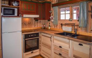 a kitchen with wooden cabinets and a white refrigerator at Cozy Home In Tuddal With Kitchen in Tuddal