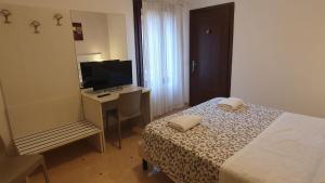 um quarto com uma cama, uma secretária e uma televisão em Casa del Pozzo em Veneza