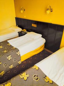 two beds in a room with yellow walls at SPOR HOTEL in Ankara