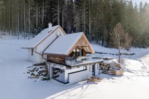 une cabine dans la neige avec de la neige sur le toit dans l'établissement Heselehof Waldchalets, à Langenwang