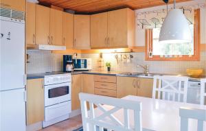 una cocina con armarios de madera y electrodomésticos blancos en Awesome Home In Djurhamn With 3 Bedrooms, en Djurhamn