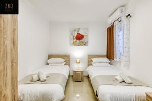 Stunning 3BR w/Country View Apartment in M'Scalak by 360 Estates في مارساسكالا: ثلاثة أسرة في غرفة بجدران بيضاء