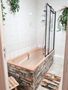 eine Badewanne im Bad mit weißen Fliesen in der Unterkunft Maison de 2 chambres avec terrasse a Deville in Deville