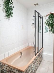 eine Badewanne im Bad mit weißen Fliesen in der Unterkunft Maison de 2 chambres avec terrasse a Deville in Deville