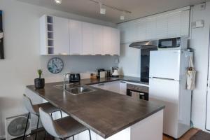 a kitchen with a white refrigerator and a counter top at Centrally Located Light-filled Studio w Parking in Auckland