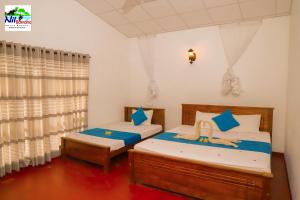 a bedroom with two beds and a window at Nil Bawana Nature Resort in Udawalawe