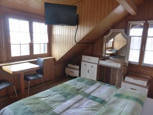 a bedroom with a bed and a desk and windows at Alpenblick Ferenberg Bern in Stettlen