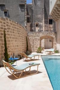 une cour avec une piscine et des chaises ainsi qu'un bâtiment dans l'établissement Palazzo Tafuri, à Nardò