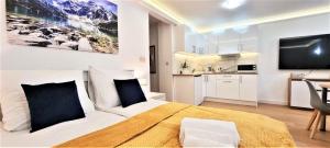 a bedroom with a large bed and a kitchen at VIP Apartamenty Tetmajera Centrum in Zakopane