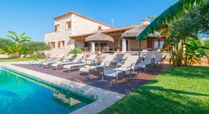 a group of chairs sitting on a deck next to a pool at Villa Es Figueral in Campos