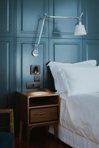 a bed with a night stand next to a bed with a lamp at The Bold Type Hotel, a Member of Design Hotels in Patra