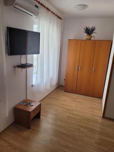 a living room with a tv and a wooden cabinet at Malin Guesthouse in Skradin