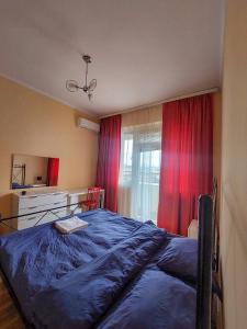 a bedroom with a blue bed and red curtains at Prishtina Center Hostel in Prishtinë