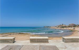 a beach with two benches and the ocean at Beautiful Home In Grammichele With Kitchenette in Grammichele