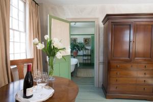 una habitación con una mesa con un jarrón de flores blancas en The Old Inn On The Green, en New Marlborough