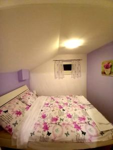 um pequeno quarto com uma cama com colcha floral em KUĆA ZA ODMOR JURINO GNIJEZDO em Jarki Horvatićevi