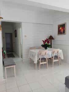 een witte tafel met stoelen en een vaas met bloemen erop bij Hanizz Vacation Home in Kampong Bukit Darat