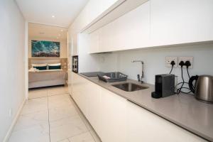 a white kitchen with a sink and a bed at Magnificent apartment 506 The Granger in Cape Town