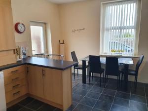 cocina con mesa, sillas y reloj en Pomfret House, in Burnley Central, Ideal for Contractors with Free Parking and Wifi en Burnley