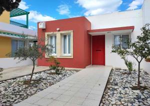 a red and white house with a red door at Villa Poseidon in Pervolia