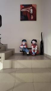 dos muñecas sentadas en las escaleras bajo una pintura en Къща за гости Алекс en Sinemorets