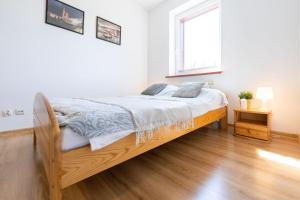- une chambre blanche avec un lit en bois dans l'établissement Apartament Bukowy z bilardem, à Wisła