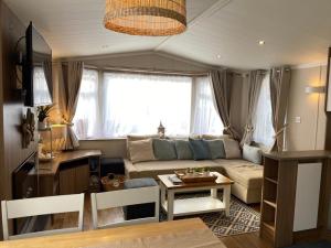 ein Wohnzimmer mit einem Sofa und einem Tisch in der Unterkunft Cosy, coastal themed Holiday Home, Rockley Park, Poole, Dorset in Poole