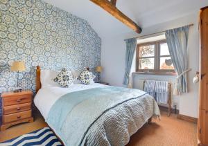 een slaapkamer met een bed met een blauwe muur bij Lilac Barn in Swanton Abbot