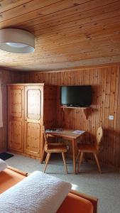 Zimmer mit einem Schreibtisch und einem TV in einer Hütte in der Unterkunft Gasthof Surselva in Brigels