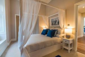 a bedroom with a canopy bed with blue pillows at Beautiful Beach side Apartment in Torquay