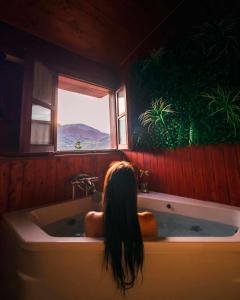 a woman sitting in a bath tub looking out a window at La Congosta mágica aldea rodeada de montañas in La Plaza
