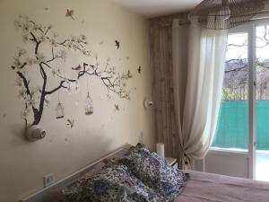 a bedroom with a tree with birds on the wall at Appartement Cap Vern Les Bains in Capvern