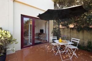 eine Terrasse mit einem Tisch, Stühlen und einem Sonnenschirm in der Unterkunft Praia da Granja - Seaside Beach in Arcozelo