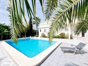 a swimming pool in front of a house with a palm tree at Detached villa with private pool in La Mata