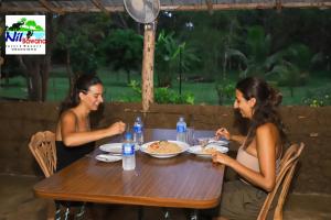 zwei Frauen sitzen an einem Tisch und essen Essen in der Unterkunft Nil Bawana Nature Resort in Udawalawe