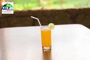 a glass of orange juice with a lime on a table at Nil Bawana Nature Resort in Udawalawe