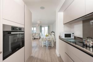 a kitchen with white cabinets and a dining room at Wish You Were Here, Crantock in Newquay