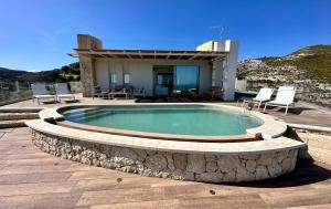a swimming pool with a stone patio and a house at Villa Olimpo in Avola