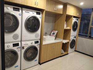 a laundry room with three washing machines and a sink at Paco Hotel Datang Metro Guangzhou-Free shuttle bus for canton fair in Guangzhou