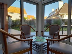 - une terrasse couverte avec 2 chaises, une table et des fenêtres dans l'établissement Gite Troubadour - Cap Gris Nez - piscine, à Audinghen