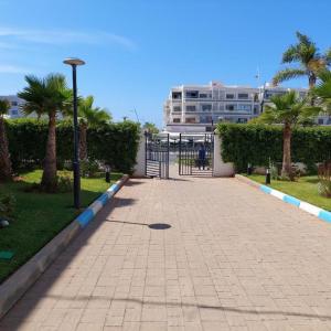 a brick walkway with palm trees and a building at Appartement avec piscine in Mohammedia +7 photos