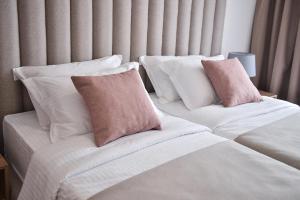 2 Betten mit weißen und rosa Kissen in einem Zimmer in der Unterkunft Magnolia Place in Tivat