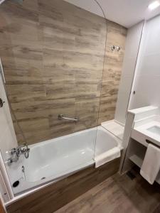 a bathroom with a shower and a tub and a sink at Hotel Albatros in Gandía