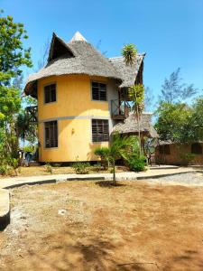 uma casa amarela com uma palmeira em frente em Kikambala Eco Villas em Mombasa