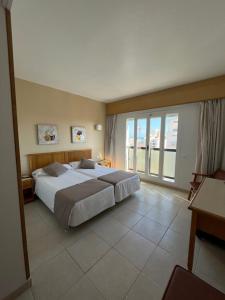 a bedroom with a large bed and a large window at Hotel Albatros in Gandía