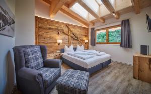 a bedroom with a bed and a chair at AlpenParks Hotel & Apartment Sonnleiten in Saalbach Hinterglemm