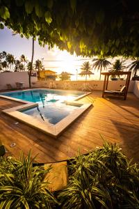 a swimming pool with a sunset in the background at Pousada Mariluz in Maragogi